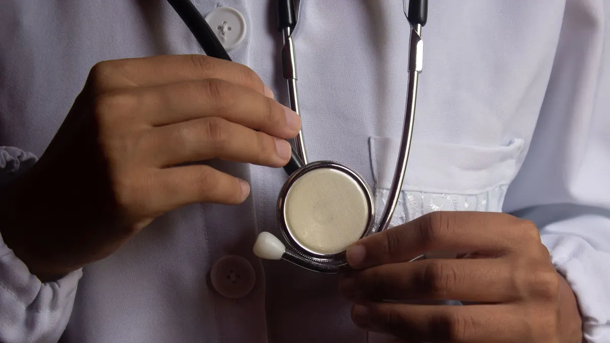 A close-up image showing a doctor holding a stethoscope, symbolizing healthcare and medical practice.