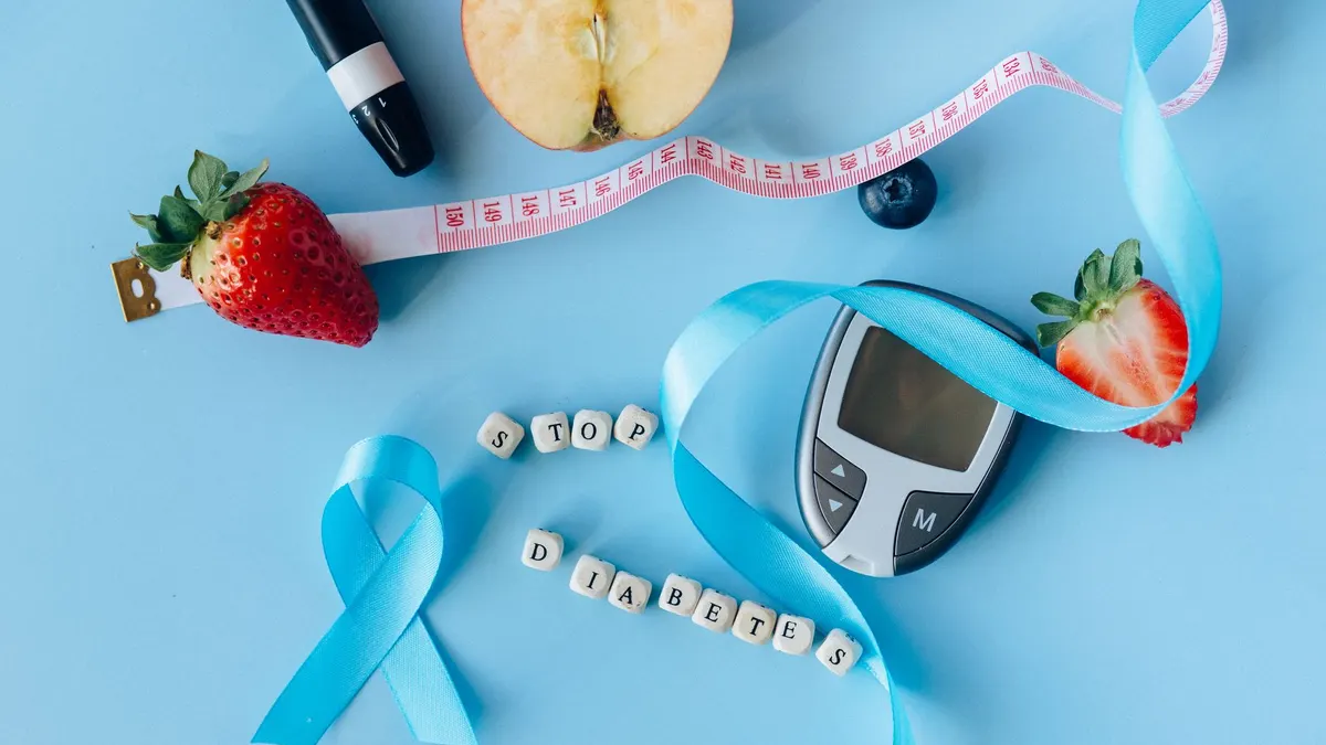 Creative diabetes awareness with fruits, glucometer, and ribbon on blue background.
