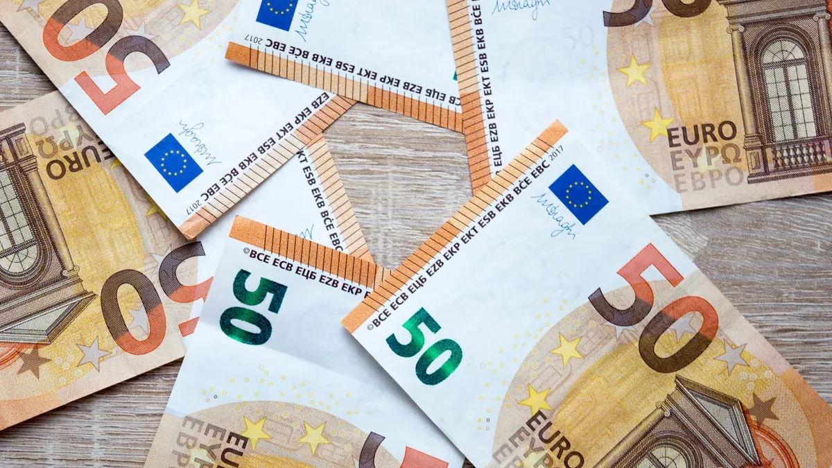 Top-down view of scattered 50 euro banknotes on a wooden surface, showcasing currency details.