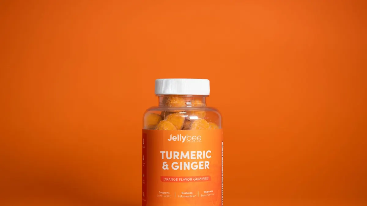 Bright image of Jellybee Turmeric & Ginger gummies in a plastic bottle against an orange backdrop.